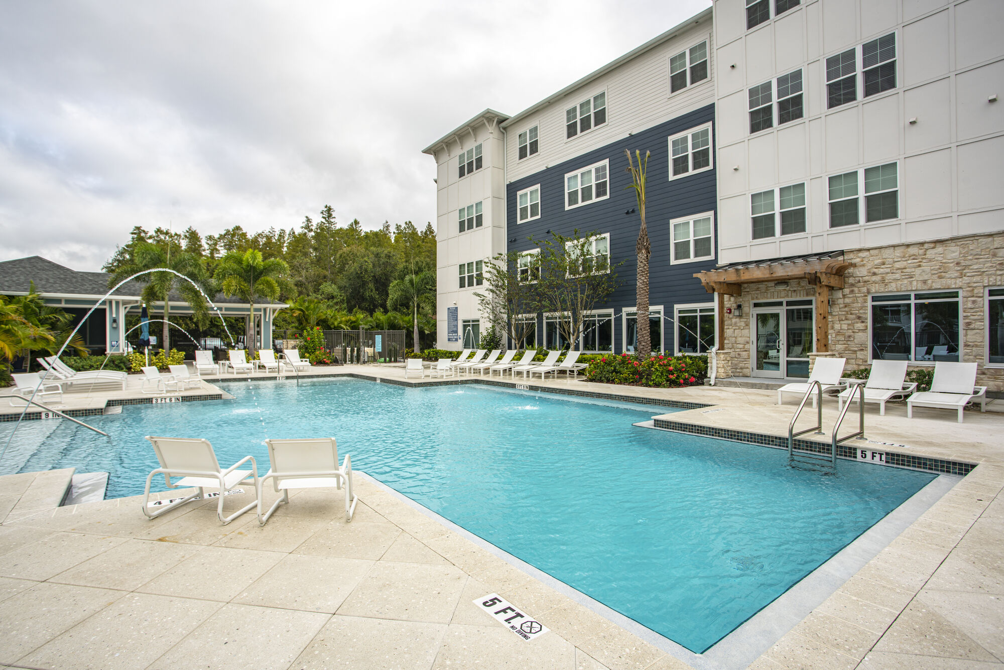 Large swimming pool with deck furniture and palm trees